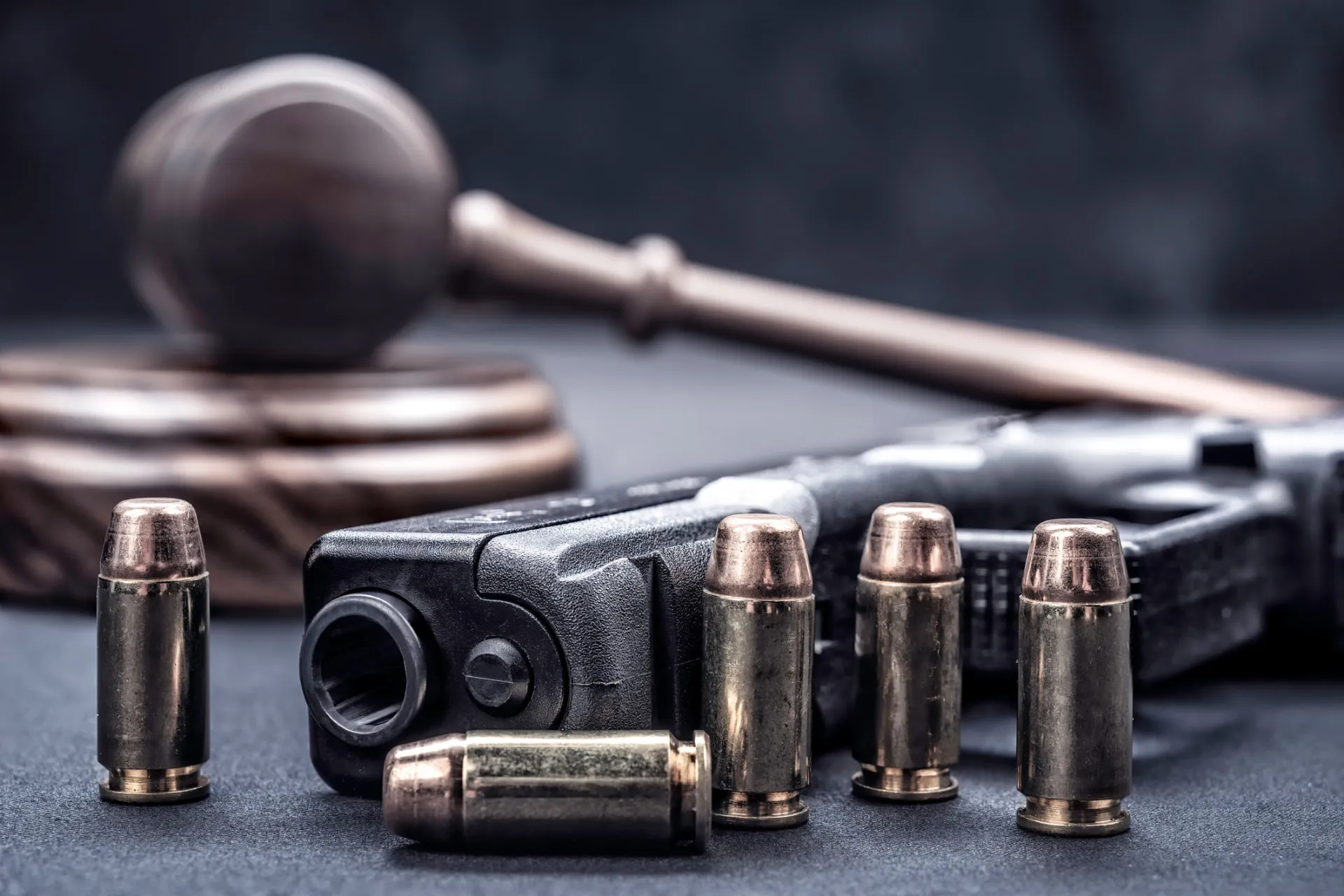 Richterhammer, Pistole und Munition auf dunklem Untergrund – Symbolbild Waffenrecht