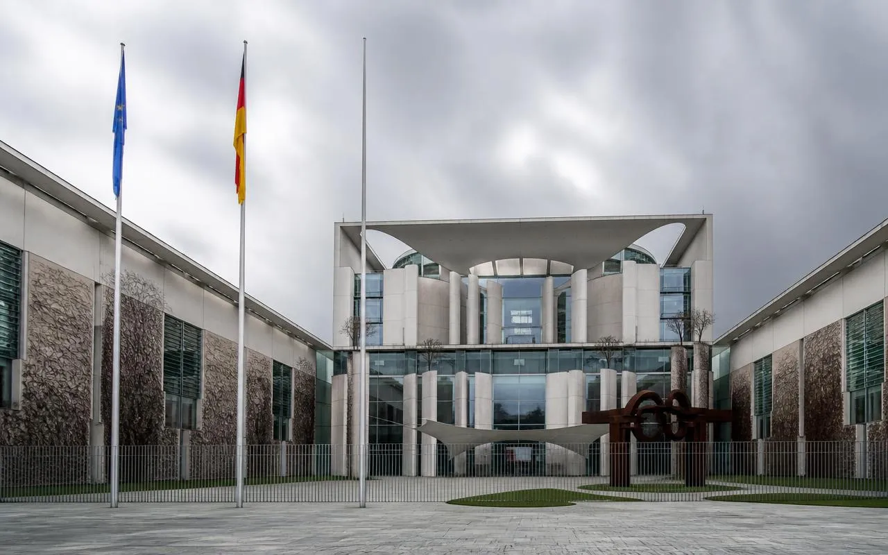 Regierungsgebäude in Berlin mit deutscher und europäischer Flagge – Symbolbild für die Evaluierung des Waffenrechts
