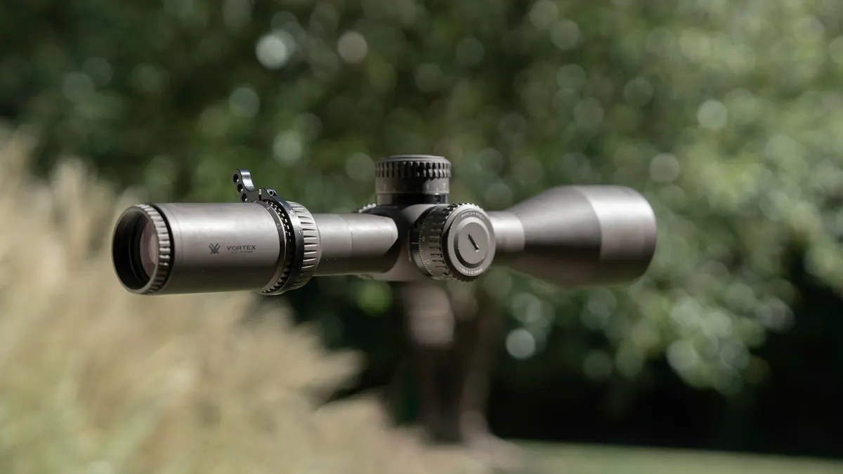 Sportpistole mit Rotpunktvisier, Munition und Chronograph auf dunklem Holz